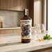 Cockburn's Port bottle on a kitchen counter with glasses of white wine and a window in the background.