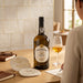Bottle of Ferreira Branco Seco Porto with a glass on a table, person sitting next to it.