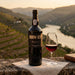 BIN 27 PORT bottle with a glass of red wine on a scenic background