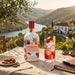 Graham's Blend No.12 Port wine bottle with a glass of red wine and garnishes on a scenic outdoor table.
