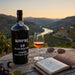 Kopke 10 Year Old Tawny Porto bottle with a glass of wine on a wooden table with a scenic background.