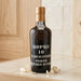 Kopke 10 Years Old White Porto bottle on a wooden surface with a tiled wall background