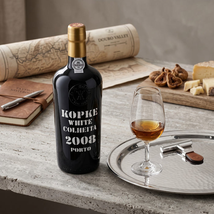 Kopke White Colheita 2008 Porto bottle with a glass of wine on a wooden table.