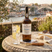 Vista Alegre Porto Port bottle with a glass of water and lemon on a stone table with a scenic background.