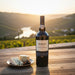 Bottle of Warre's Port wine with a plate of cheese on a wooden table with a scenic background