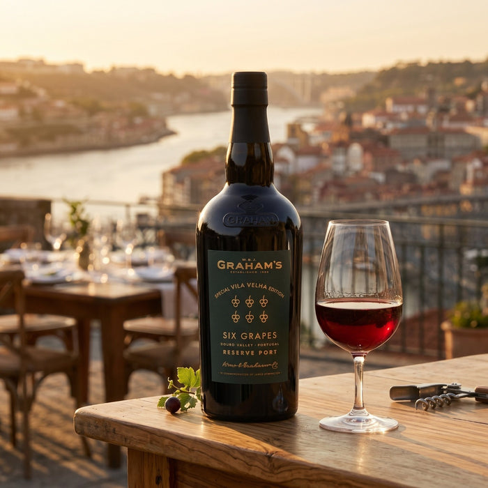 Graham's Port bottle with a glass of wine on a wooden table with a scenic background.